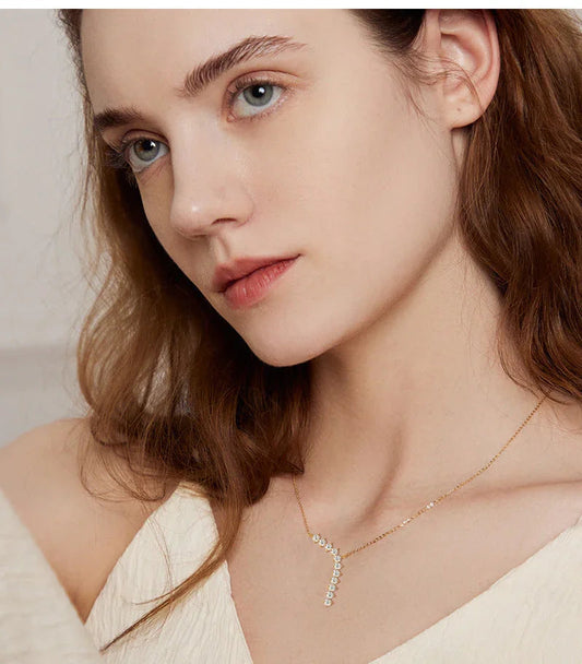 Woman wearing gold necklace with curved diamond pendant, minimal jewelry style