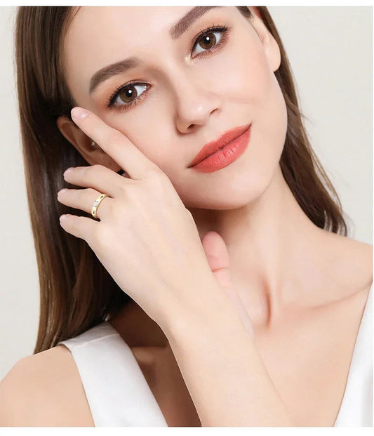 Woman with natural makeup wearing a gold ring on finger, close up jewelry fashion shot
