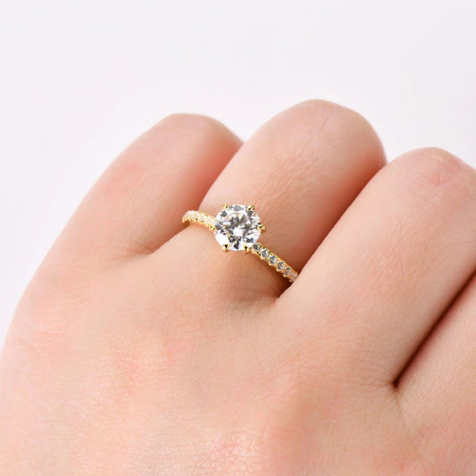 Gold solitaire diamond engagement ring with pavé band on hand
