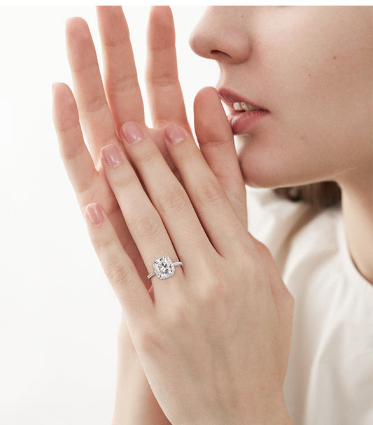 Woman wearing cushion cut diamond engagement ring with pave band