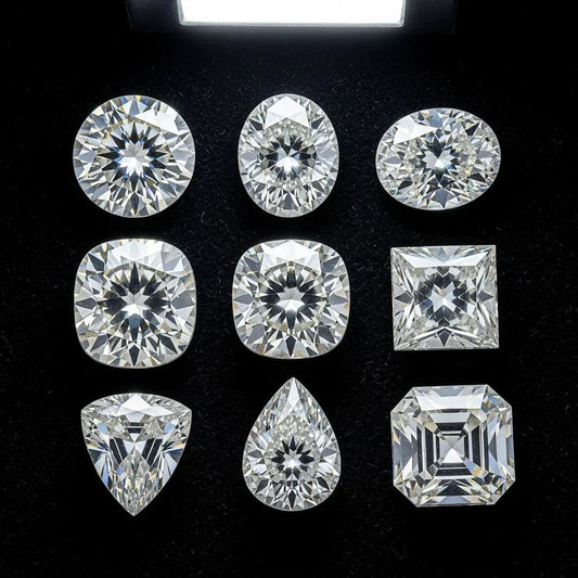Nine loose diamonds of various cuts on black background under bright light