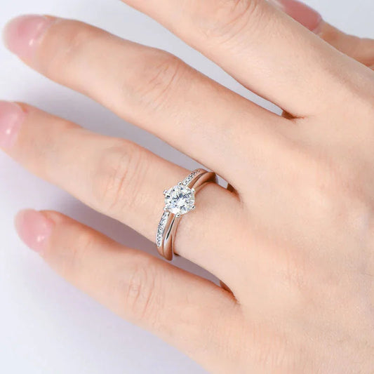 Hand wearing a silver diamond solitaire engagement ring with side stones