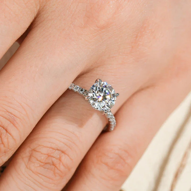 Close-up of hand wearing a silver diamond solitaire engagement ring with pave band