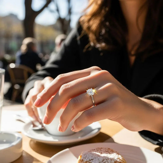Woman wearing moissanite engagement ring at outdoor cafe with coffee and pastry